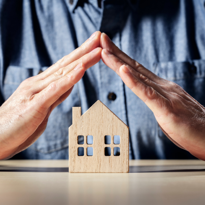 Mãos protegendo casa